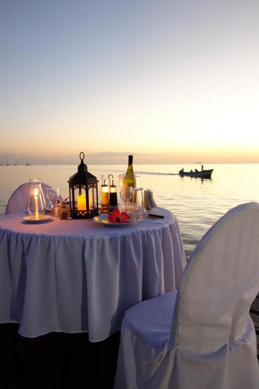 a table with a lantern and two chairs next to the water at Splash Inn Dive Resort & Villas in West End