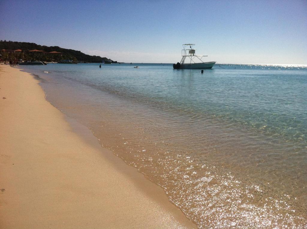 a boat in the water next to a beach at Splash Inn Dive Resort & Villas in West End