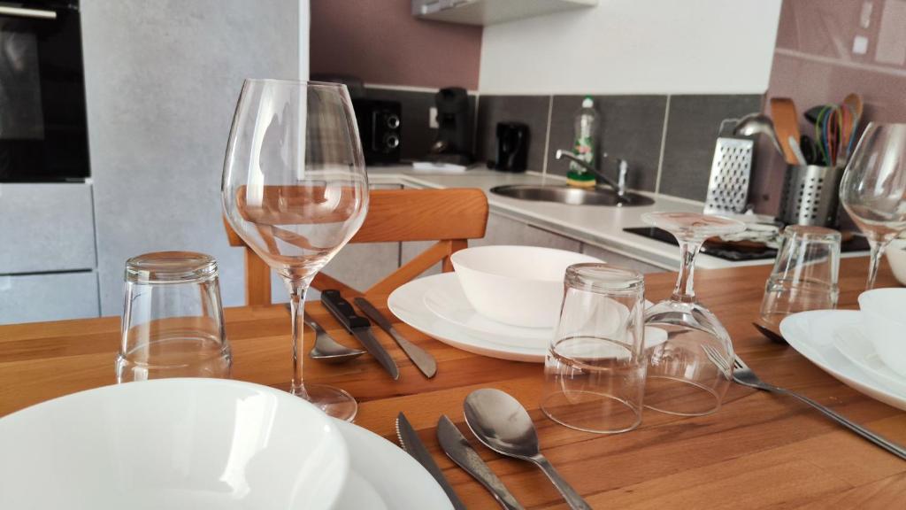 - une table en bois avec des verres à vin et des assiettes dans l'établissement Escapade à Lourdes dans beau T2 avec terrasse - Proche Gare et Centre ville, à Lourdes