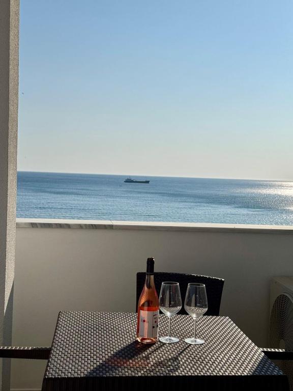 a bottle of wine sitting on a table with two wine glasses at Apartamente Antoni Shengjin in Shëngjin