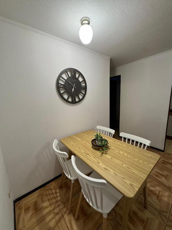 a dining room table with chairs and a clock on the wall at Departamento en Quillota in Quillota