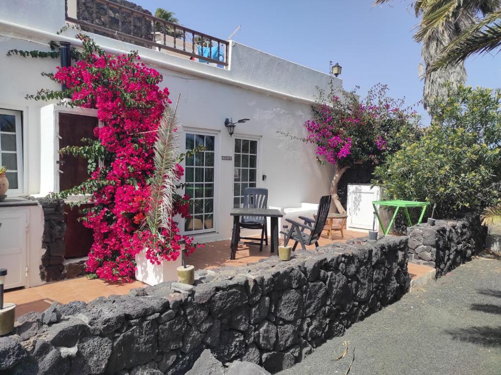 una casa con fiori rosa su un muro di pietra di Verde casa eden a Tías