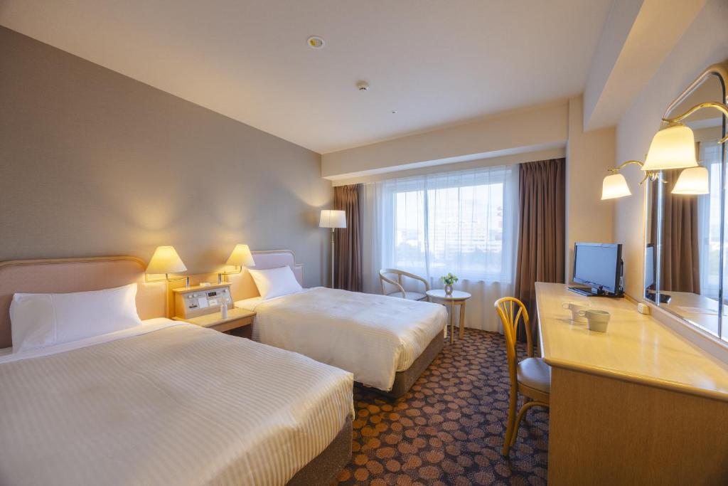 a hotel room with two beds and a television at Hotel Fujita Fukui in Fukui