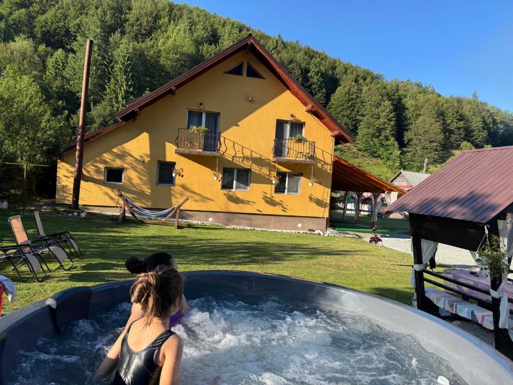 a woman in a hot tub in front of a house at Casa Natalia Raisa Arieșeni in Arieşeni