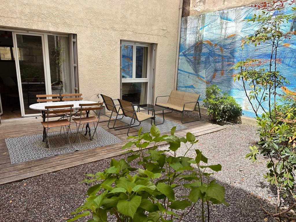 un patio avec une table et des chaises devant un bâtiment dans l'établissement Apartment with Garden 1 bedroom 3 people, à Bordeaux