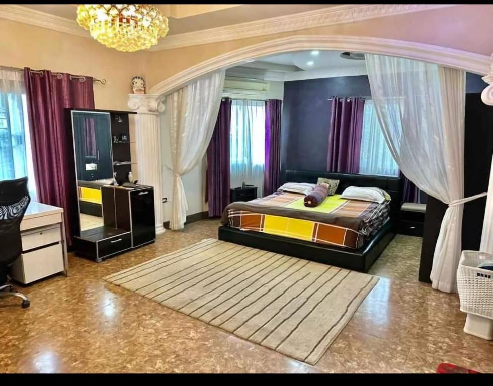 ein Schlafzimmer mit einem Bett und einem Fernseher darin in der Unterkunft Pattaya Paradise Pool villa with Garden 3BR in Nong Prue