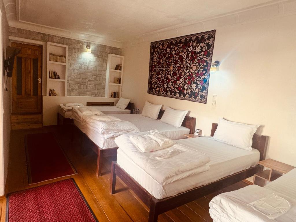 a room with four beds and a painting on the wall at MUSLIMA HOTEL Boutique in Bukhara