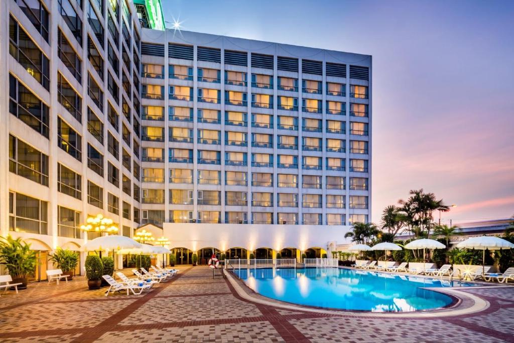 a hotel with a swimming pool in front of a building at Bangkok Palace Hotel in Bangkok