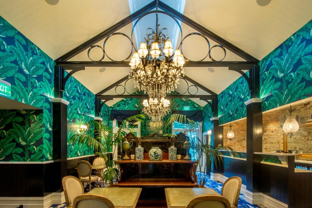 a dining room with a chandelier and green walls at Hulbert House Luxury Boutique Lodge Queenstown in Queenstown