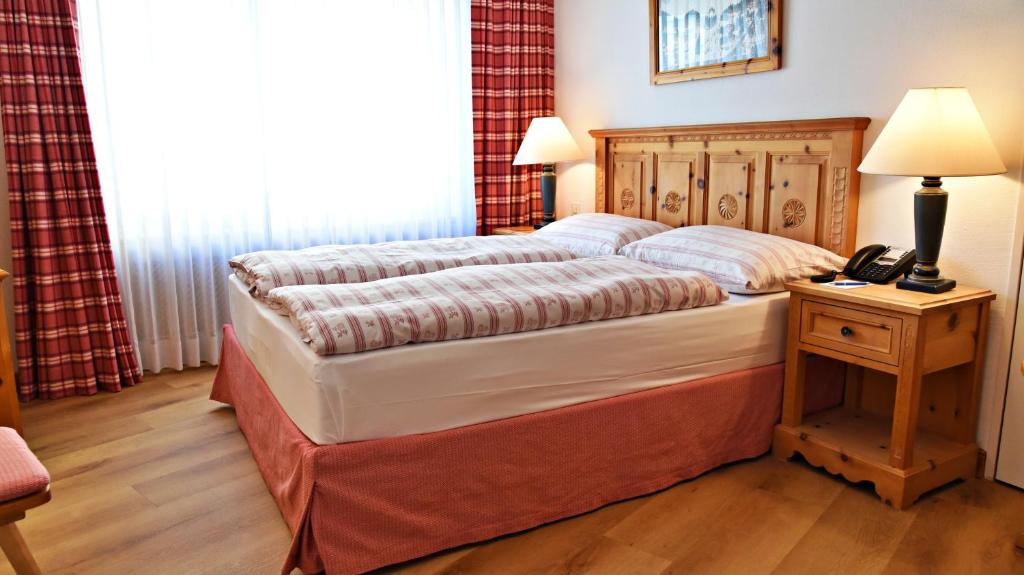 a bedroom with a bed with a phone on a table at Crystal Hotel superior in St. Moritz
