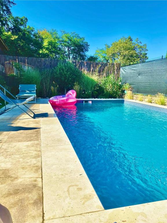 une piscine avec un bateau rose dans l'eau dans l'établissement Le Clos des hirondelles, à Veyrignac