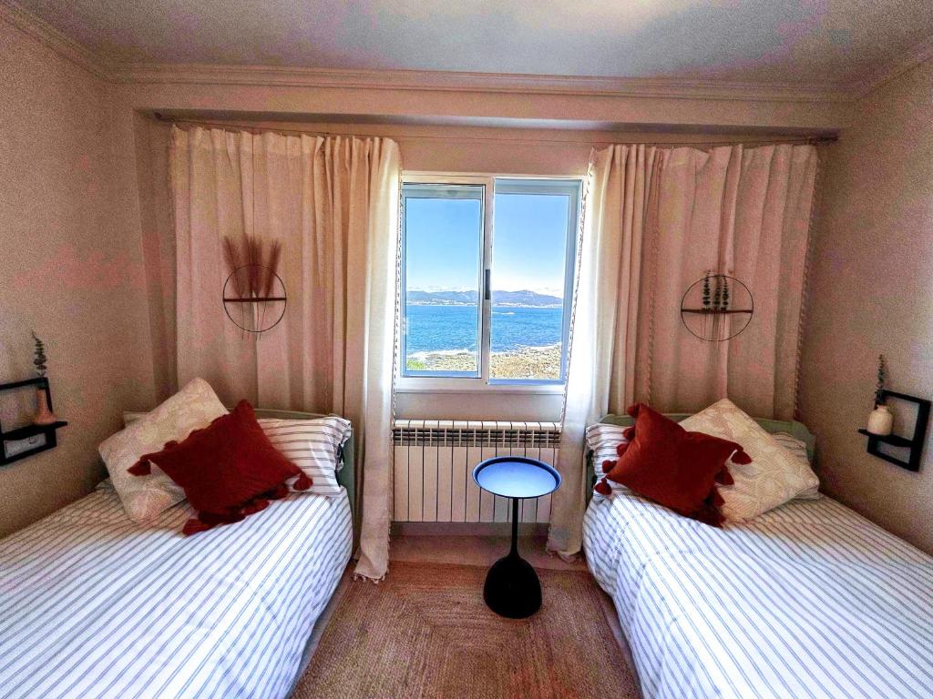 two beds in a room with a window at OLarDasOlas - Casa con jardin frente al mar, Porto do Son in Porto do Son