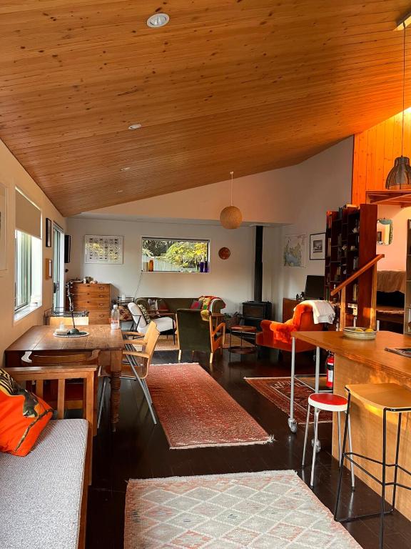 a living room with wooden ceilings and tables and chairs at Queens Drive in Oneroa