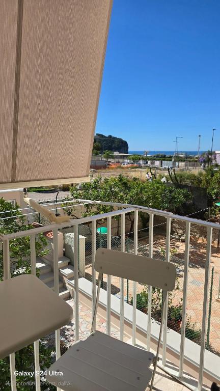 a white chair and table on a balcony with the beach at Alloggio turistico Dedicato in Gaeta