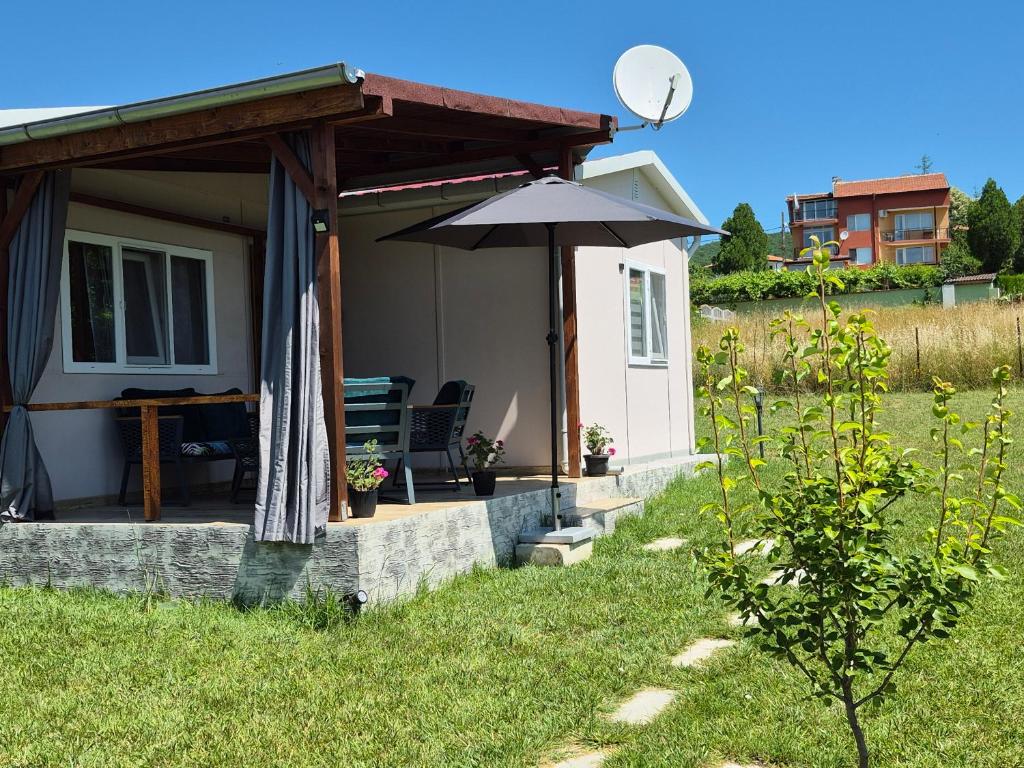a small house with an umbrella and a table at Къщички Sunrise in Tsarevo