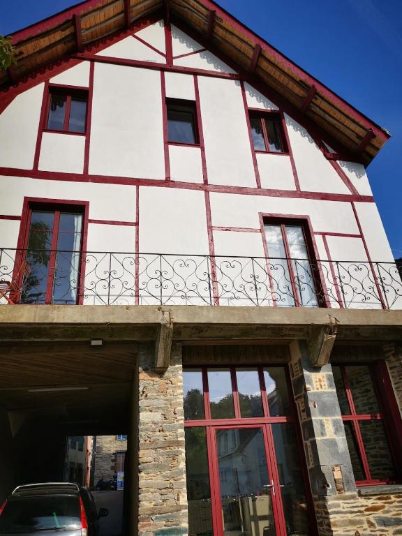 - un bâtiment blanc et rouge avec un balcon dans l'établissement La Basque - un balcon au coeur de La Gacilly, à La Gacilly