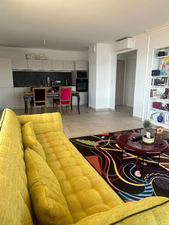 un salon avec un canapé jaune et une table dans l'établissement Beautiful Appartment Les terrasses de Torretta room sea view Ajaccio, à Ajaccio