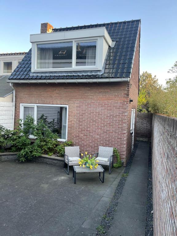 a house with two chairs and a table in front of it at Wendy's Tiny Beachhouse in Noordwijk