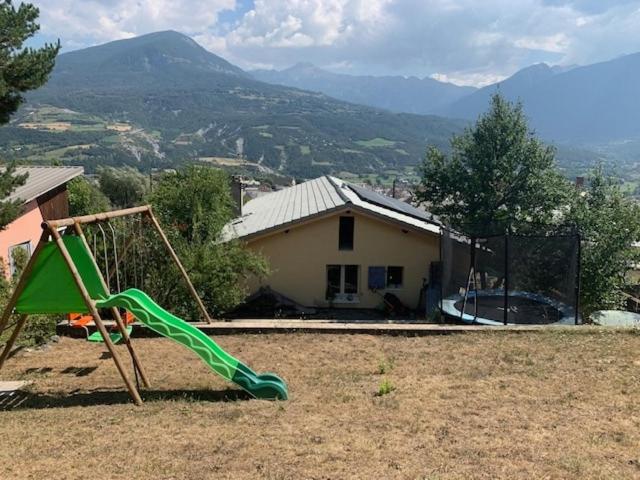 une aire de jeux avec toboggan en face d'une maison dans l'établissement Maison individuelle 130 m2 4 Chambres, à Embrun