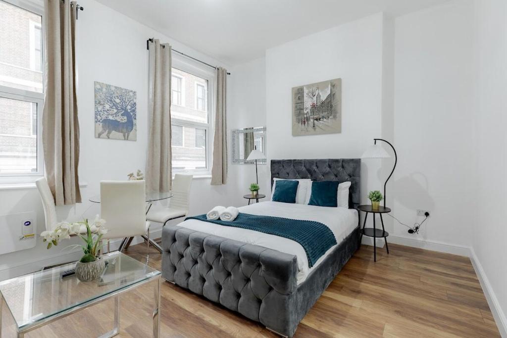 a bedroom with a large bed with blue pillows at Nestio - Paddington Serviced Studios! in London