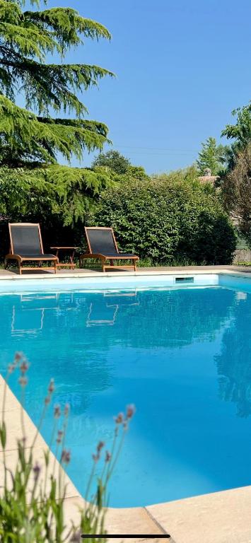 two chairs sitting next to a swimming pool at Cocon nature proche Bordeaux in Saint-André-de-Cubzac