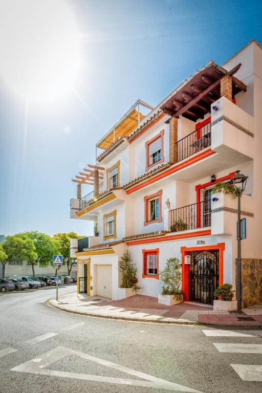 a large white building with red doors on a street at La Casa Del Maestro in Estepona