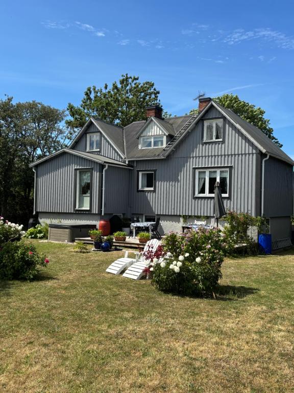 een groot grijs huis met een tuin bij Charmig Ölandsgård in Köpingsvik