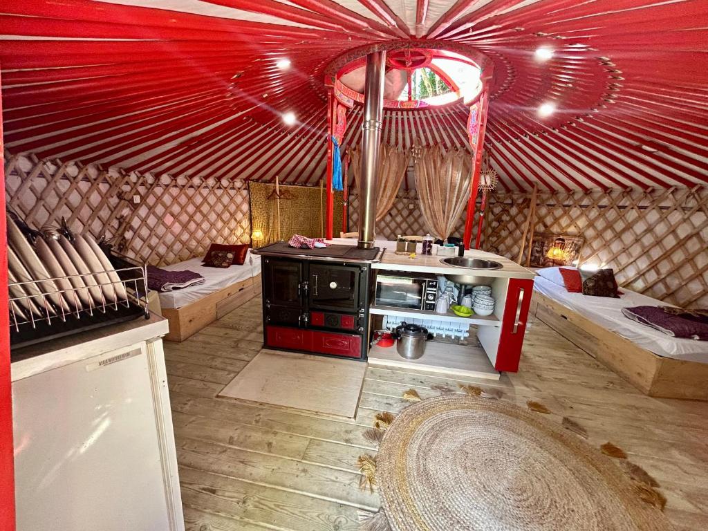 une cuisine dans une yourte avec deux lits et un poêle dans l'établissement Ravissant yourte traditionnelle, à Quimper