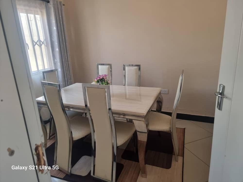 a dining room table with chairs and a wooden table at Luta Serviced Apartment in Lusaka