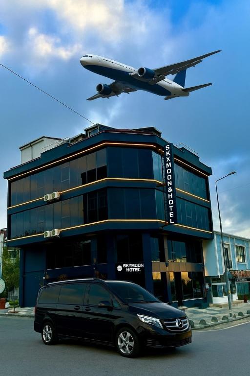 an airplane flying over a building with a van parked in front at Skymoon Istanbul Airport Hotel in Arnavutköy