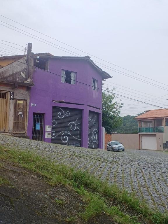 a purple house with a car parked in front of it at Dona Maria - Quartos in Rio Grande da Serra