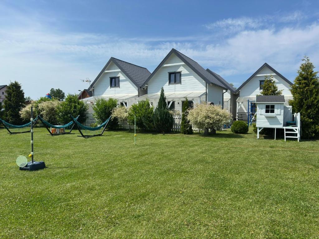a house with a yard with a swing at Domki Kalipso in Sarbinowo