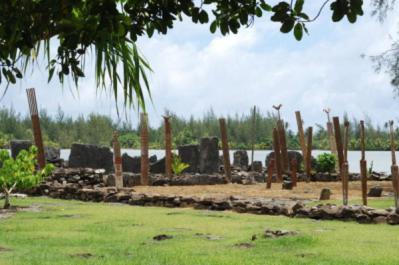 a group of wooden posts in a field with a body of water at B & Bee Wild Island - Nature Song in Fare
