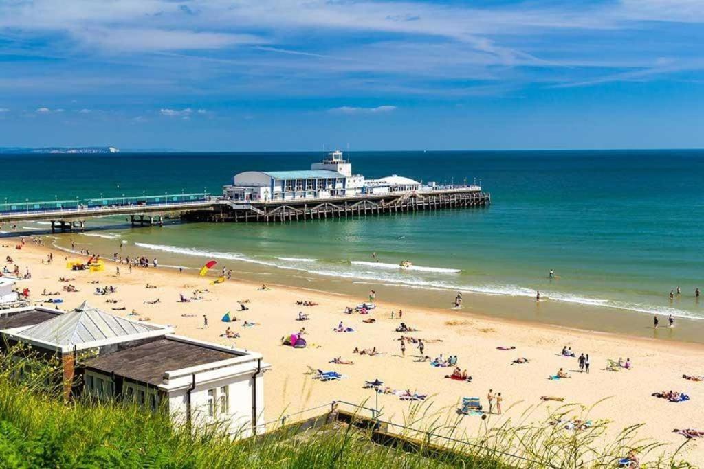 ein Strand mit einem Pier und Menschen auf dem Sand in der Unterkunft Double Room with share in Parkstone