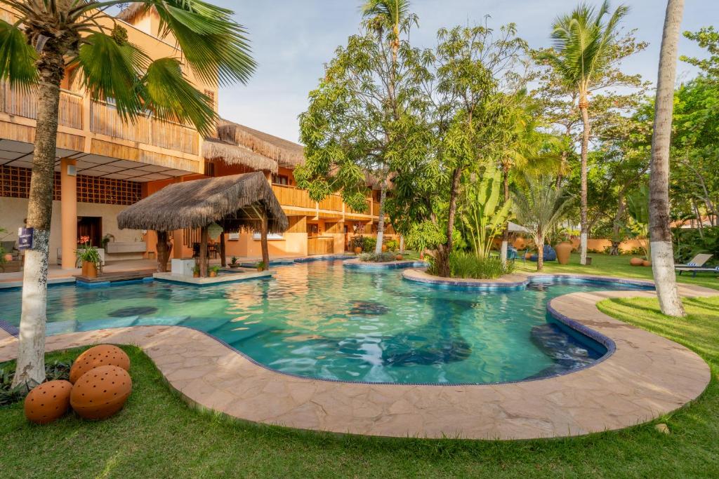 una piscina frente a un edificio con palmeras en Dayo Hotel, en Flecheiras