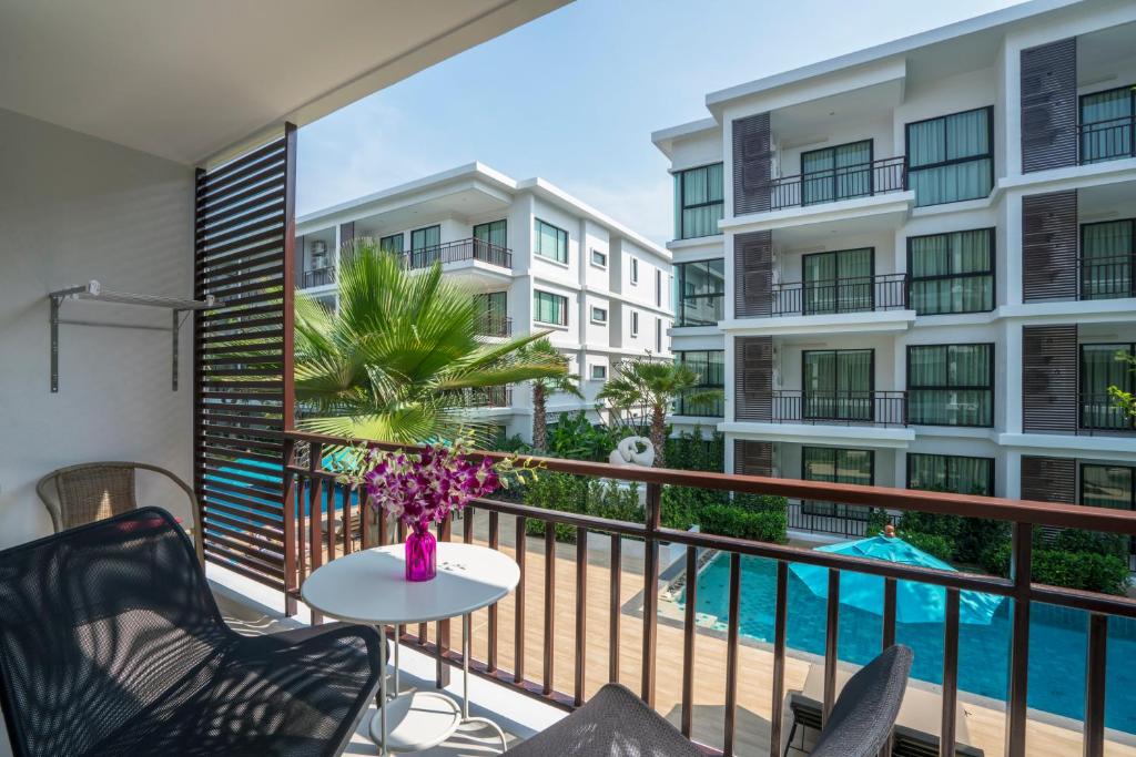 ein Balkon mit Tisch und Stühlen und ein Pool in der Unterkunft Apartments in The Title Beach Rawai in Rawai Beach