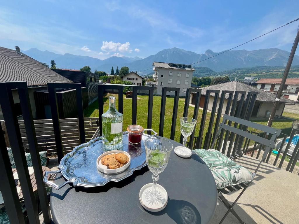 une table avec une bouteille et des verres sur un balcon dans l'établissement Les enfants gâtés, à Albertville