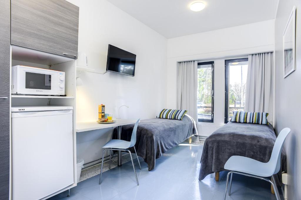 a kitchen with a table, chairs and a microwave at Forenom Hostel Vantaa Aviapolis in Vantaa