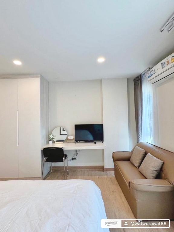 a bedroom with a bed and a couch and a tv at อีสต์วิลล์บางแสน36 in Ban Hua Khao Sammuk