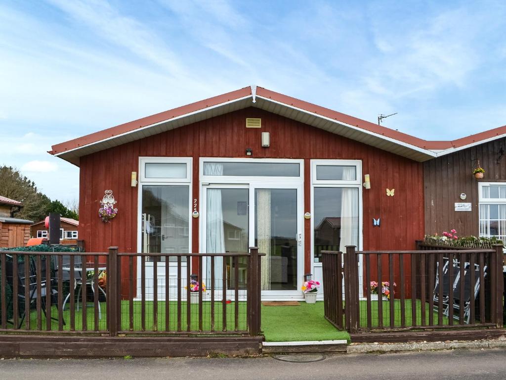 a red house with a fence in front of it at Yeolde Woodern Country View Seashak - Uk46596 in Bridlington