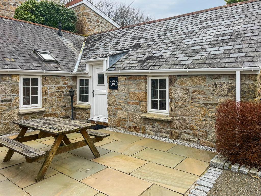 a wooden picnic table in front of a stone cottage at The Piggery - Uk49014 in Liskeard