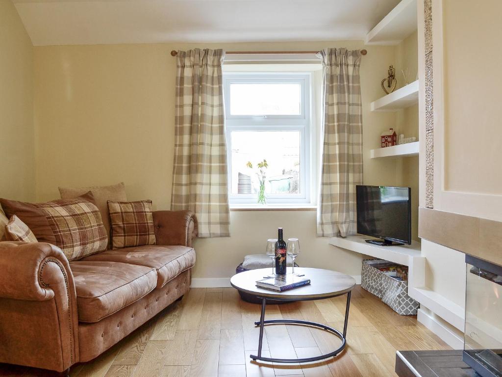 Una sala de estar con un sofá y un televisor. en Jessamine Cottage, en Blairgowrie