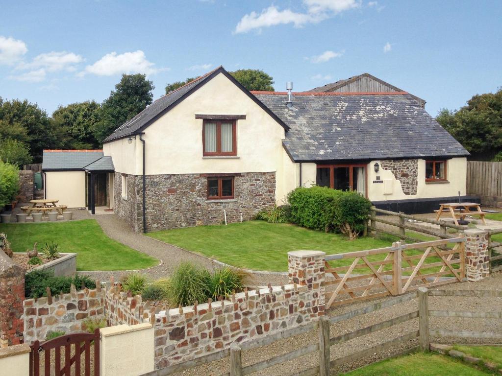a house with a stone fence in front of it at The Imaginary Barn in Hartland