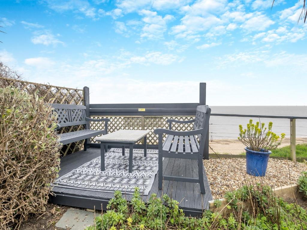a patio with a table and a bench and the ocean at Beachside House in Scratby
