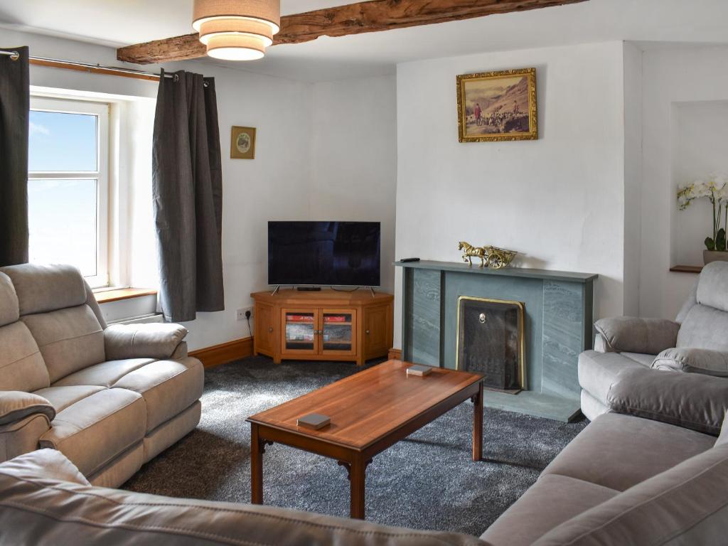 a living room with two couches and a fireplace at Uk46833 - Low Hollas Farmhouse in Threlkeld