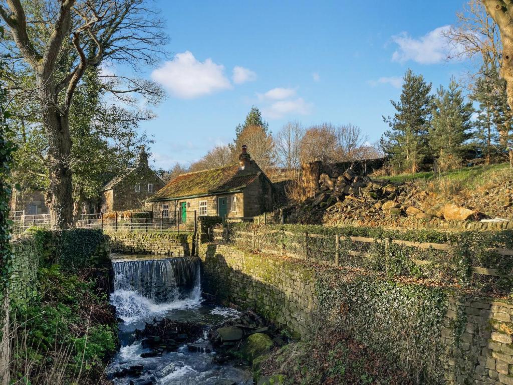 ein Bach in einem Dorf mit einem Wasserfall in der Unterkunft Mill Close Cottage in Chesterfield
