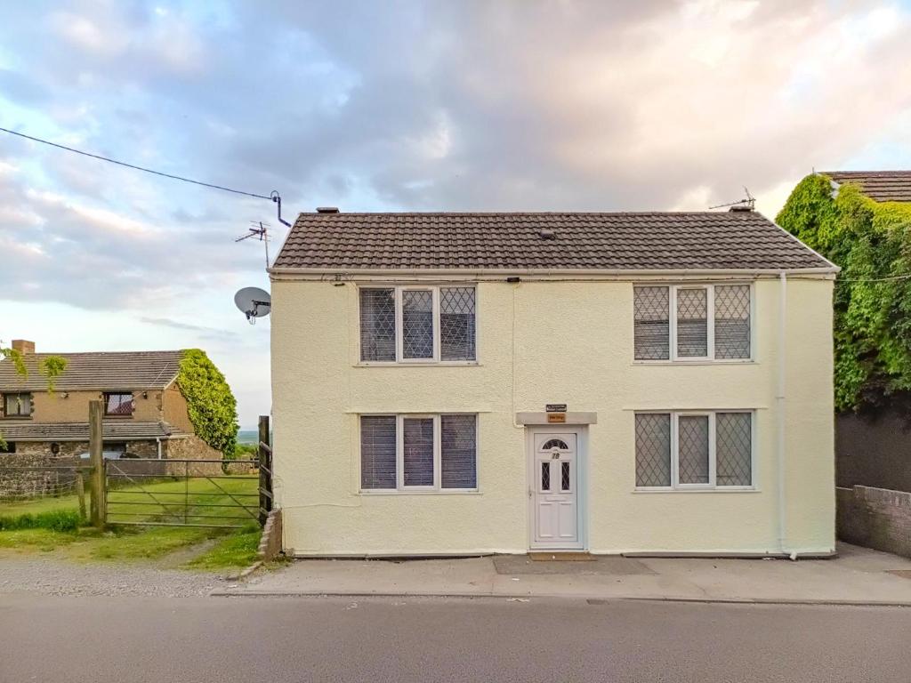 a white house with a white door on a street at Elder Cottage in Bridgend
