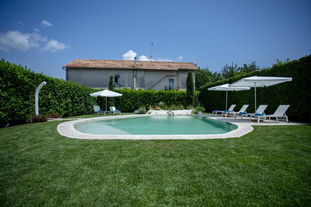 a swimming pool with chairs and umbrellas in a yard at Divina Costiera in Agerola