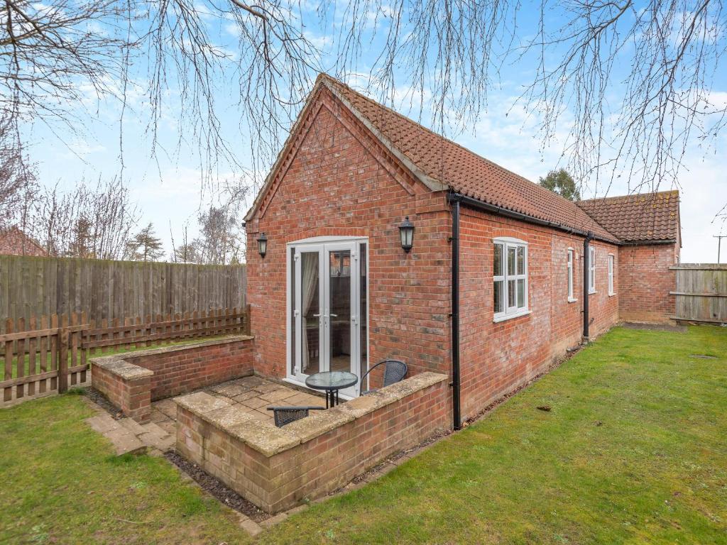 a small brick house with a chair in a yard at Primrose Cottage - Uk48563 