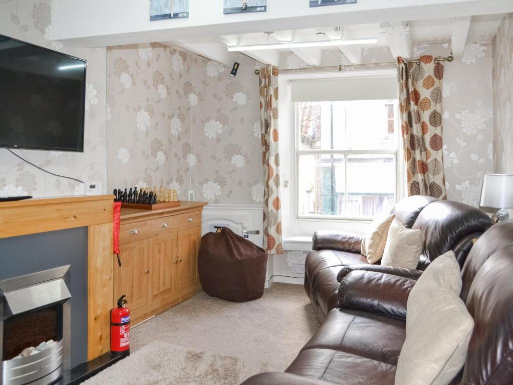 a living room with a leather couch and a television at Ashlors in Bridlington